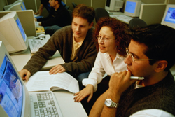picture of three students in a computer lab working together