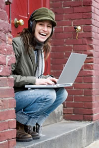 young woman on doorstep listening to computer